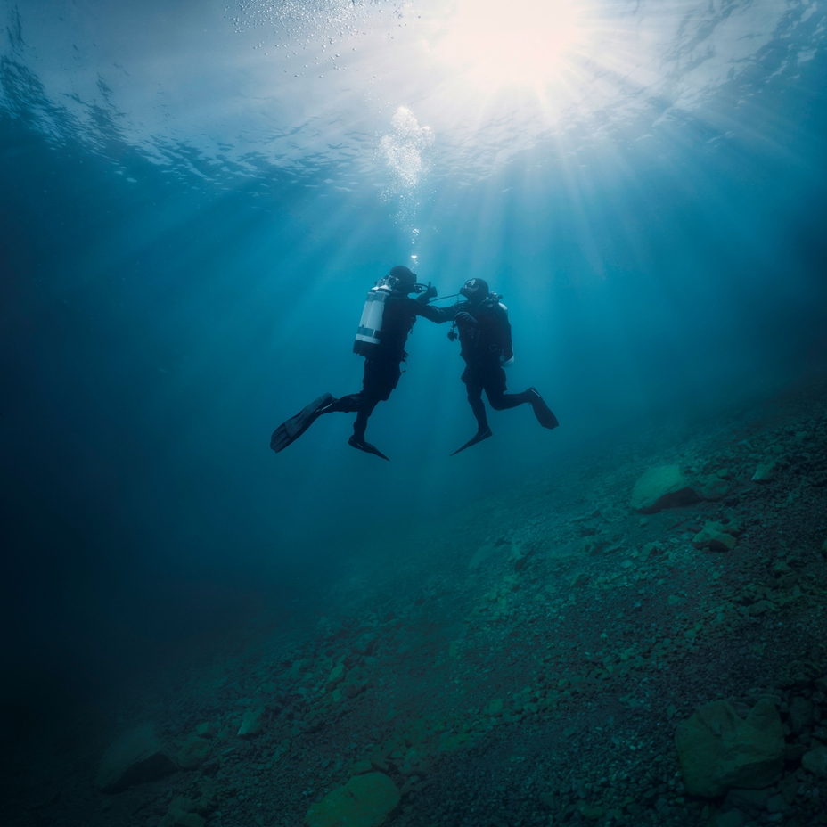 Onderwaterscène: een duiker ondersteunt een tweede duiker die problemen heeft met zijn luchtvoorziening.